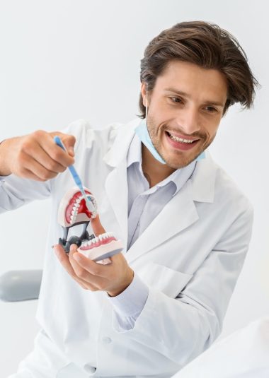 cheerful-doctor-showing-how-to-brush-teeth-using-jaw-model.jpg
